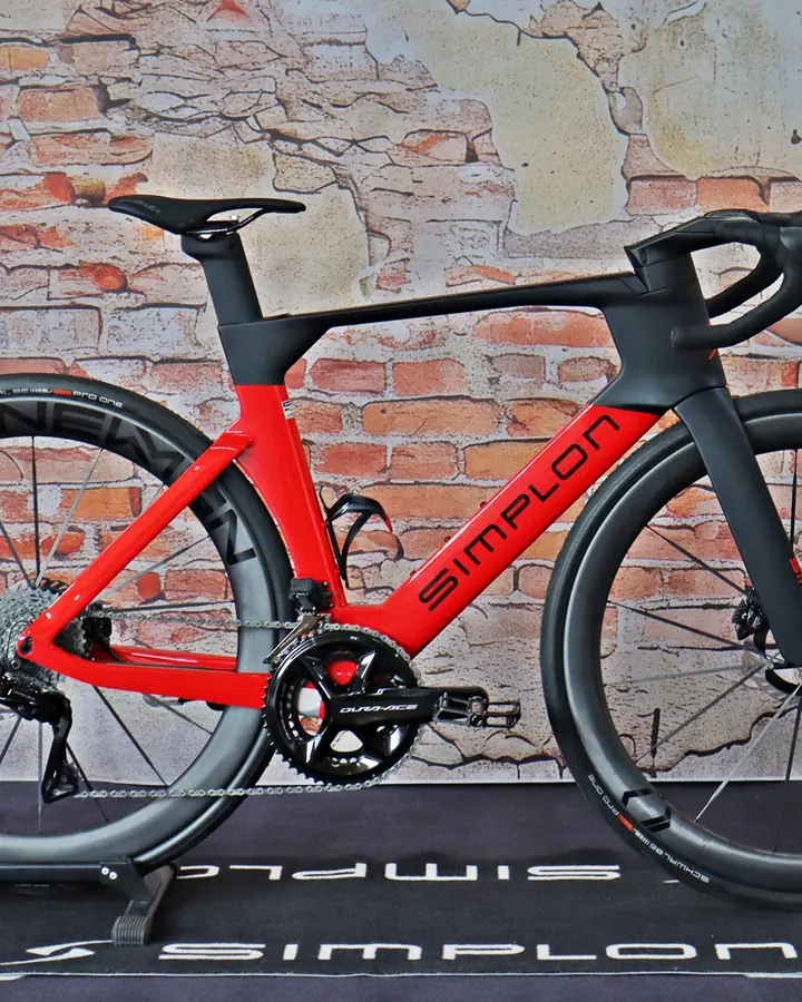 Rotes Simplon-Rennrad vor der Ziegelwand im Laden